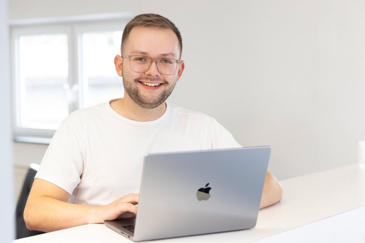 Ein Mann mit Brille arbeitet an einem Apple MacBook